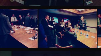 Movie still from “9/11: Inside the President's War Room” (2021), directed by Adam Wishart – A group of people sitting around a conference table; Medium shot, High angle