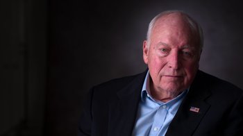 Movie still from “9/11: Inside the President's War Room” (2021), directed by Adam Wishart – An older man wearing a jacket and a blue shirt; Close Up shot, Low angle