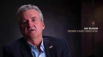 Movie still from “9/11: Inside the President's War Room” (2021), directed by Adam Wishart – An older man wearing a suit and a blue shirt; Close Up shot, Low angle
