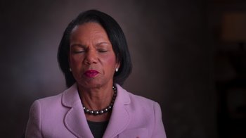 Movie still from “9/11: Inside the President's War Room” (2021), directed by Adam Wishart – A woman that is wearing a pink jacket; Close Up shot, Low angle