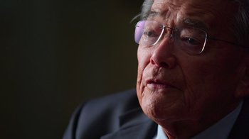 Movie still from “9/11: Inside the President's War Room” (2021), directed by Adam Wishart – An older man wearing glasses and wearing a suit; Extreme Close Up shot, High angle