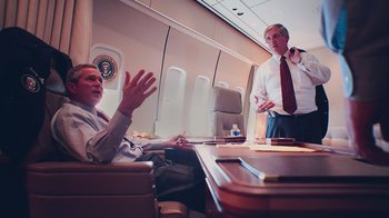 Movie still from “9/11: Inside the President's War Room” (2021), directed by Adam Wishart – Two men sitting at a table in an airplane; Medium shot, High angle