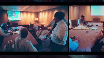 Movie still from “9/11: Inside the President's War Room” (2021), directed by Adam Wishart – A man in a suit and tie sitting in front of two other men in a room; Wide shot, High angle