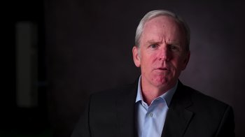 Movie still from “9/11: Inside the President's War Room” (2021), directed by Adam Wishart – An older man wearing a suit and a blue dress shirt; Close Up shot, Low angle