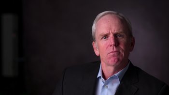 Movie still from “9/11: Inside the President's War Room” (2021), directed by Adam Wishart – An older man wearing a suit and a blue dress shirt; Close Up shot, Low angle