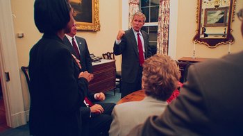 Movie still from “9/11: Inside the President's War Room” (2021), directed by Adam Wishart – A group of people sitting in a room; Medium shot, Over the shoulder angle