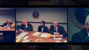 Movie still from “9/11: Inside the President's War Room” (2021), directed by Adam Wishart – Three men sitting at a table in front of a white house; Medium shot, High angle
