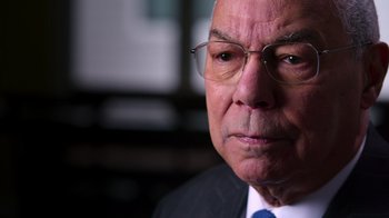 Movie still from “9/11: Inside the President's War Room” (2021), directed by Adam Wishart – An older man wearing glasses and a suit and tie; Close Up shot, Low angle