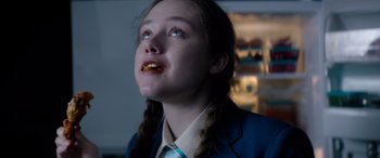 Movie still from “A Banquet” (2021), directed by Ruth Paxton – A young girl with a bite of food in her mouth; Close Up shot, Low angle