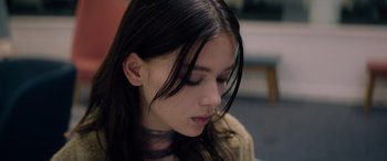 Movie still from “A Banquet” (2021), directed by Ruth Paxton – A young woman with long black hair looking down at her face; Close Up shot, Low angle