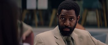 Movie still from “A Banquet” (2021), directed by Ruth Paxton – A person wearing a suit and tie; Close Up shot, Over the shoulder angle