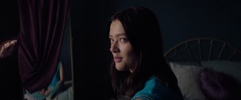 Movie still from “A Banquet” (2021), directed by Ruth Paxton – A woman with long dark brown hair looking to her left; Close Up shot, Over the shoulder angle