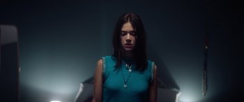 Movie still from “A Banquet” (2021), directed by Ruth Paxton – A woman in a blue shirt is standing in the dark; Medium shot, Low angle