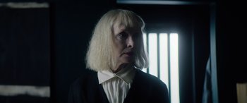 Movie still from “A Banquet” (2021), directed by Ruth Paxton – An older woman with blonde hair wearing a white shirt and a black jacket; Close Up shot, Low angle