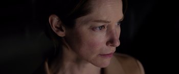 Movie still from “A Banquet” (2021), directed by Ruth Paxton – A woman's face in a dark room; Close Up shot, Low angle
