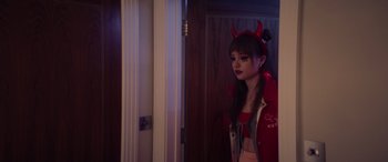 Movie still from “A Banquet” (2021), directed by Ruth Paxton – A woman in a red jacket with horns on her head; Medium shot, Over the shoulder angle