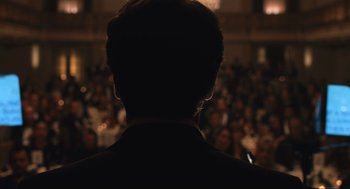 Movie still from “A Beautiful Day in the Neighborhood” (2019), directed by Marielle Heller – A man in a black suit standing in front of an audience; Extreme Close Up shot, Over the shoulder angle