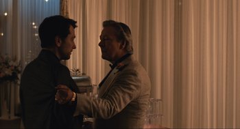 Movie still from “A Beautiful Day in the Neighborhood” (2019), directed by Marielle Heller – Two men in suits are shaking hands at a party; Medium shot, Over the shoulder angle