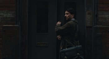 Movie still from “A Beautiful Day in the Neighborhood” (2019), directed by Marielle Heller – A man with a beard holding a black bag; Medium shot, Over the shoulder angle