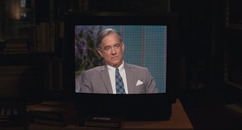 Movie still from “A Beautiful Day in the Neighborhood” (2019), directed by Marielle Heller – A man in a suit and tie sitting in front of a television; Medium shot, Over the shoulder angle