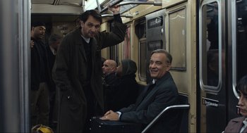Movie still from “A Beautiful Day in the Neighborhood” (2019), directed by Marielle Heller – Two men on a subway train , one of whom is sitting in a wheelchair; Medium shot, Over the shoulder angle
