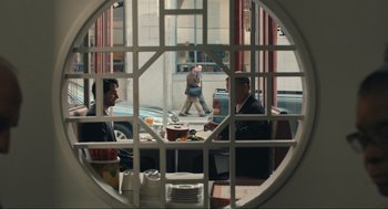 Movie still from “A Beautiful Day in the Neighborhood” (2019), directed by Marielle Heller – A group of people sitting at a table in a restaurant; Wide shot, Over the shoulder angle