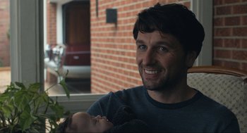 Movie still from “A Beautiful Day in the Neighborhood” (2019), directed by Marielle Heller – A man holding a baby in his arms and smiling; Close Up shot, Over the shoulder angle