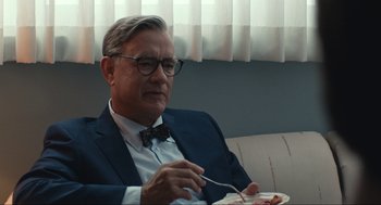 Movie still from “A Beautiful Day in the Neighborhood” (2019), directed by Marielle Heller – An older man sitting on a couch eating food; Medium shot, Over the shoulder angle