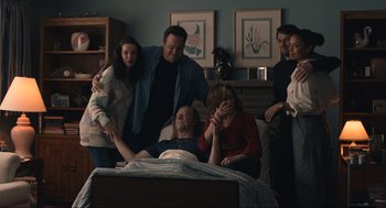 Movie still from “A Beautiful Day in the Neighborhood” (2019), directed by Marielle Heller – A group of people standing around a man in a bed; Medium shot, Over the shoulder angle