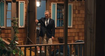 Movie still from “A Beautiful Day in the Neighborhood” (2019), directed by Marielle Heller – An older man wearing a suit and tie on a porch; Medium shot, Over the shoulder angle