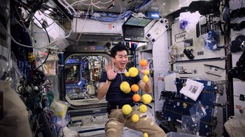 A man in a space suit holding a bunch of fruit