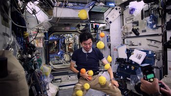 A man juggling oranges in a space station