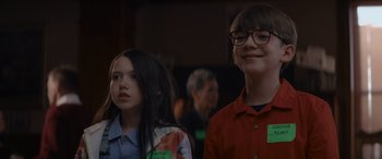 Movie still from “A Christmas Mystery” (2022), directed by Alex Ranarivelo – Two people standing next to each other in front of a crowd; Close Up shot, Over the shoulder angle