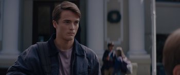 Movie still from “A Christmas Mystery” (2022), directed by Alex Ranarivelo – A young man standing in front of a white building; Close Up shot, Over the shoulder angle