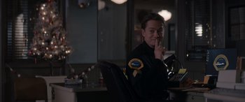 Movie still from “A Christmas Mystery” (2022), directed by Alex Ranarivelo – A police officer sitting at a table in a room; Medium shot, Over the shoulder angle