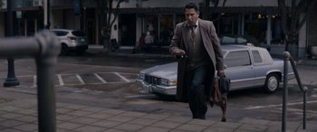 Movie still from “A Christmas Mystery” (2022), directed by Alex Ranarivelo – A man walking down the street holding a purse; Wide shot, Low angle