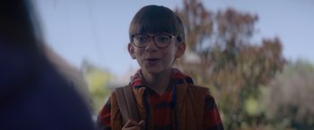 Movie still from “A Christmas Mystery” (2022), directed by Alex Ranarivelo – A young boy wearing glasses and holding a backpack; Close Up shot, Over the shoulder angle