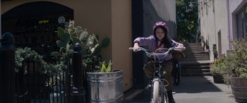 Movie still from “A Christmas Mystery” (2022), directed by Alex Ranarivelo – A young girl sitting on a bicycle next to a potted plant; Medium shot, Low angle