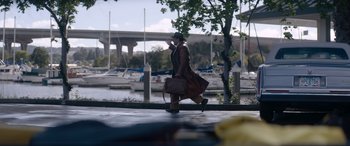 Movie still from “A Christmas Mystery” (2022), directed by Alex Ranarivelo – A man walking down a sidewalk with a bag; Wide shot, Over the shoulder angle