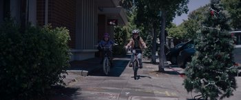 Movie still from “A Christmas Mystery” (2022), directed by Alex Ranarivelo – Two young children riding bikes down a sidewalk; Wide shot, High angle
