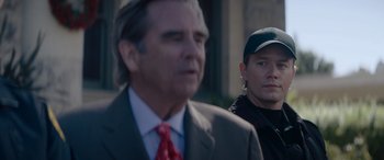 Movie still from “A Christmas Mystery” (2022), directed by Alex Ranarivelo – A man in a suit standing next to another man in a hat; Close Up shot, Over the shoulder angle