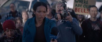 Movie still from “A Christmas Mystery” (2022), directed by Alex Ranarivelo – A woman is holding a microphone and a camera; Close Up shot, Low angle