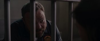 Movie still from “A Christmas Mystery” (2022), directed by Alex Ranarivelo – A man with a beard is behind bars looking at the camera; Close Up shot, Over the shoulder angle