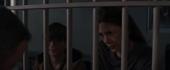 A woman and a boy behind a metal fence