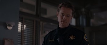 Movie still from “A Christmas Mystery” (2022), directed by Alex Ranarivelo – A man in a police uniform is looking at the camera; Close Up shot, Over the shoulder angle