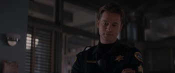 Movie still from “A Christmas Mystery” (2022), directed by Alex Ranarivelo – A man in a police uniform standing next to a wall; Close Up shot, Over the shoulder angle