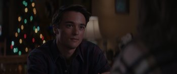 Movie still from “A Christmas Mystery” (2022), directed by Alex Ranarivelo – A young man sitting in a living room with a dog; Close Up shot, Over the shoulder angle