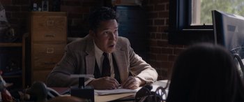 Movie still from “A Christmas Mystery” (2022), directed by Alex Ranarivelo – A man sitting at a table in front of a computer; Medium shot, Low angle