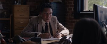 Movie still from “A Christmas Mystery” (2022), directed by Alex Ranarivelo – A man sitting at a table writing on a piece of paper; Medium shot, Over the shoulder angle