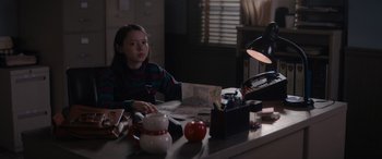 Movie still from “A Christmas Mystery” (2022), directed by Alex Ranarivelo – A girl sitting at a table in front of an apple; Medium shot, Over the shoulder angle
